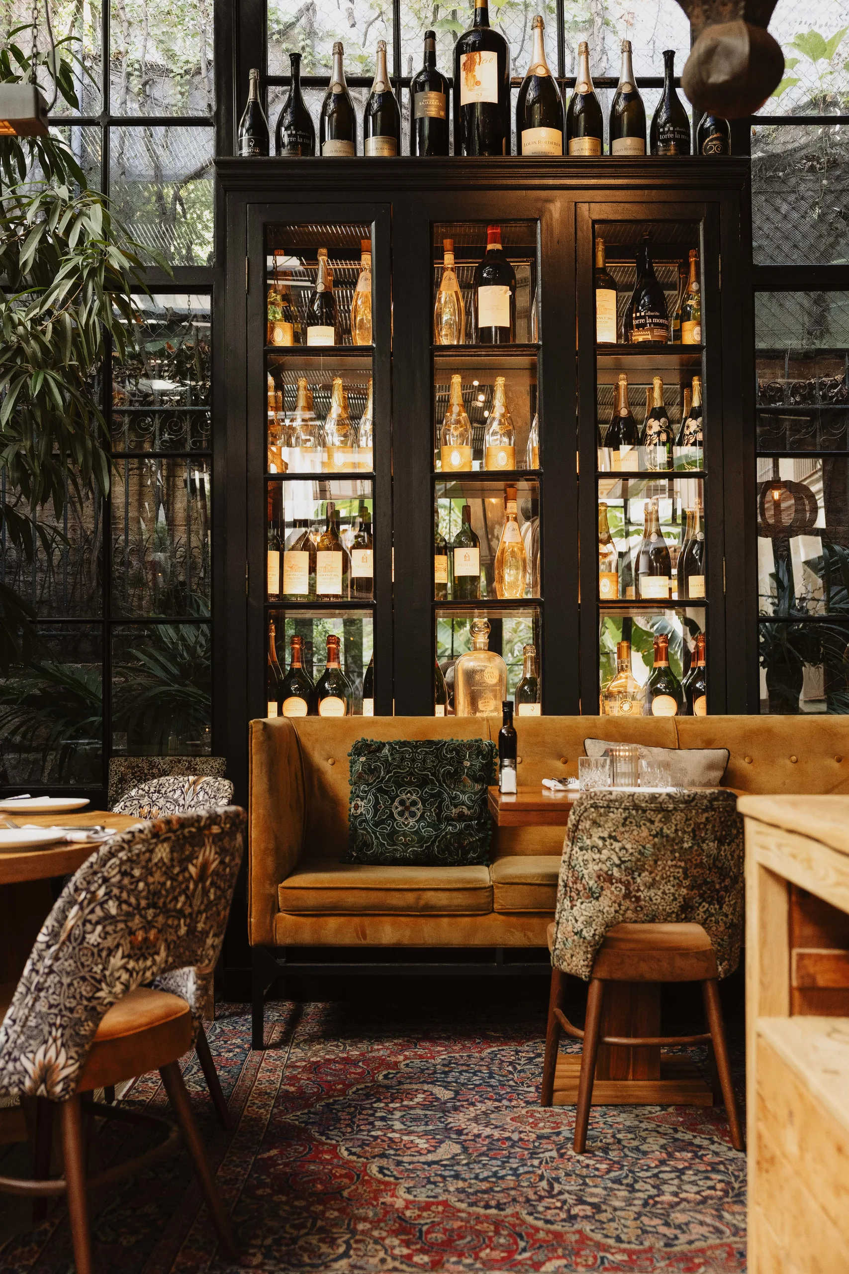 Mustard velvet banquette in front of a backlit wine cabinet