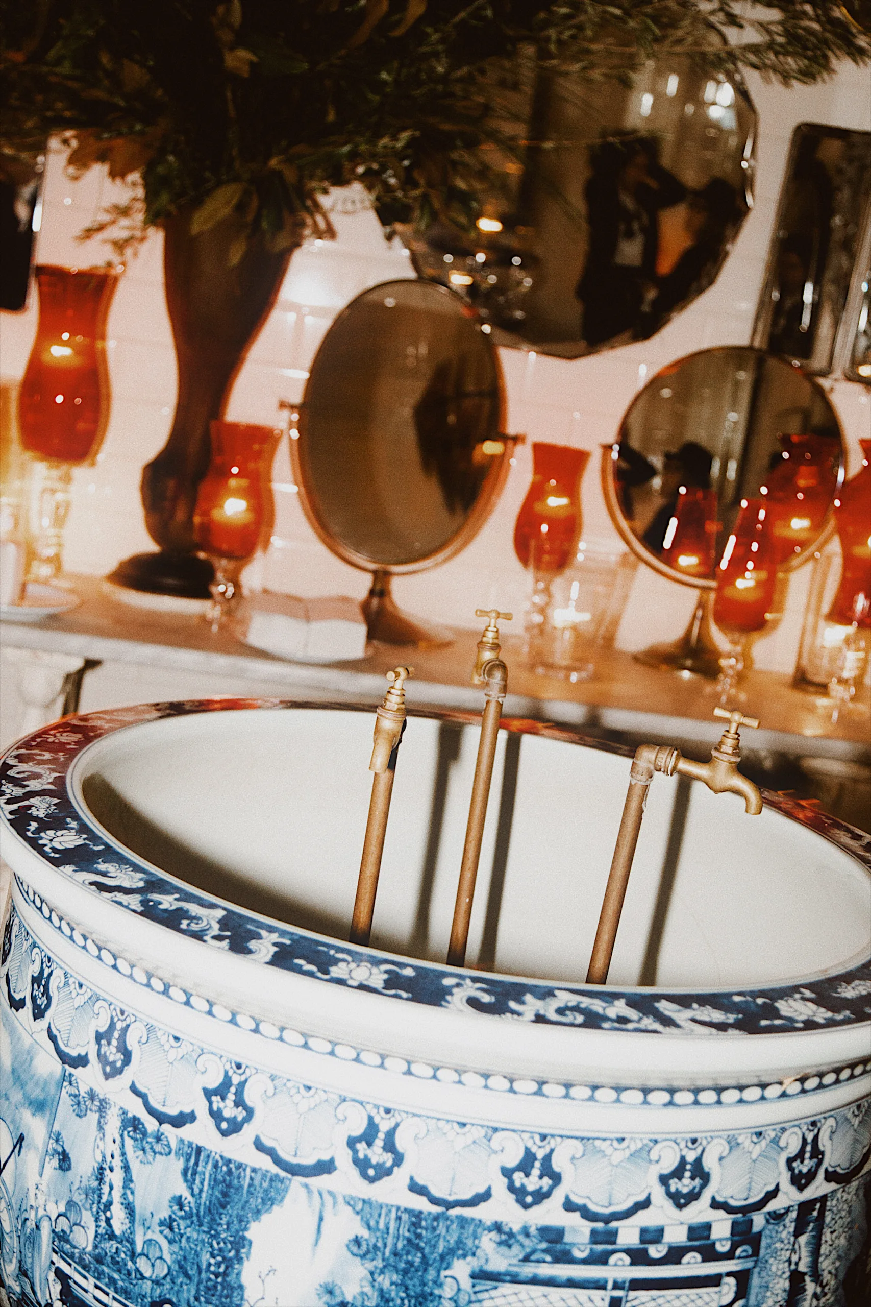 Blue-and-white porcelain basin with brass taps and red glass lamps